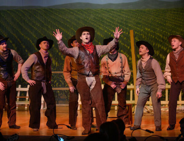 Male actors dressed as cowboys performing the Rodgers and Hammerstein musical Oklahoma!